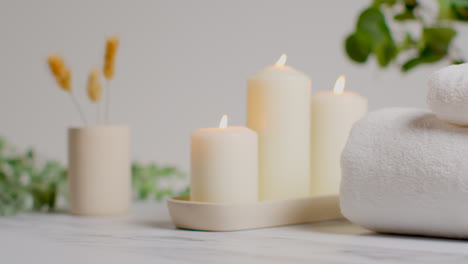 Still-Life-Of-Lit-Candles-With-Dried-Grasses-Green-Plant-And-Soft-Towels-As-Part-Of-Relaxing-Spa-Day-Decor-1